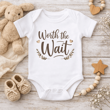 Cute baby onesies laying flat on a wooden board background.