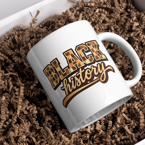 White ceramic Black History mug with cultural lettering placed in decorative gift box filler.