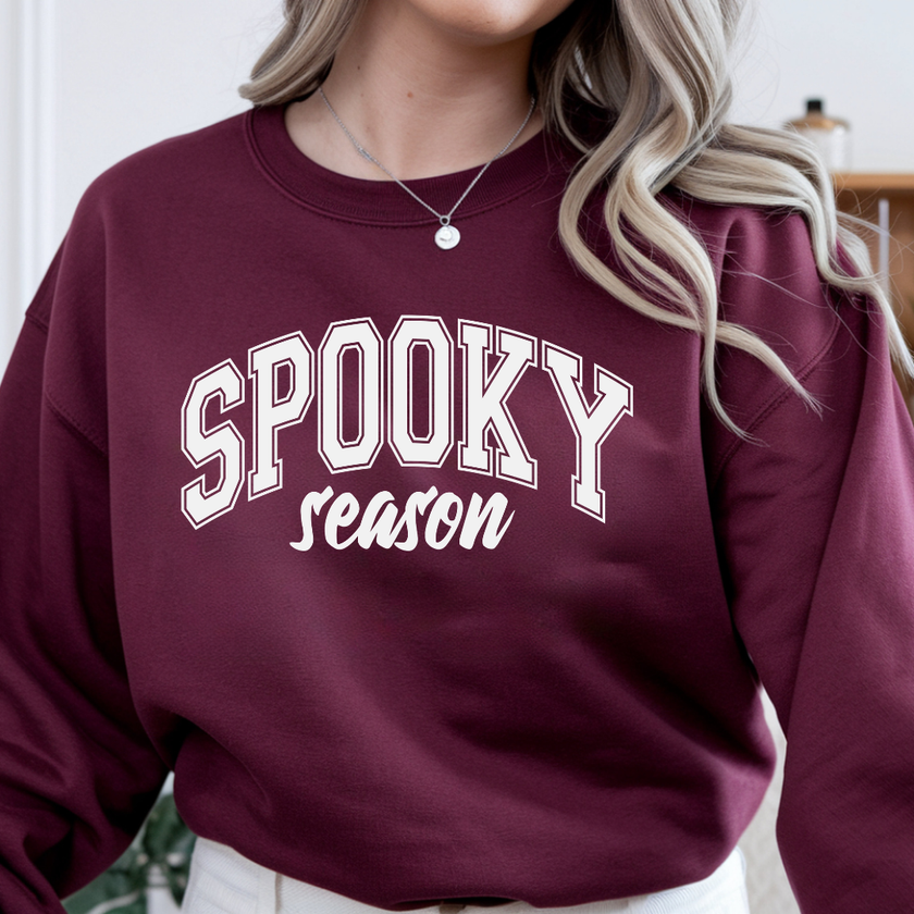 Woman modeling a garnet Spooky Season crewneck sweatshirt featuring white varsity style Halloween design