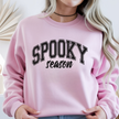 Woman wearing a light pink Spooky Season crewneck sweatshirt with black varsity Halloween lettering