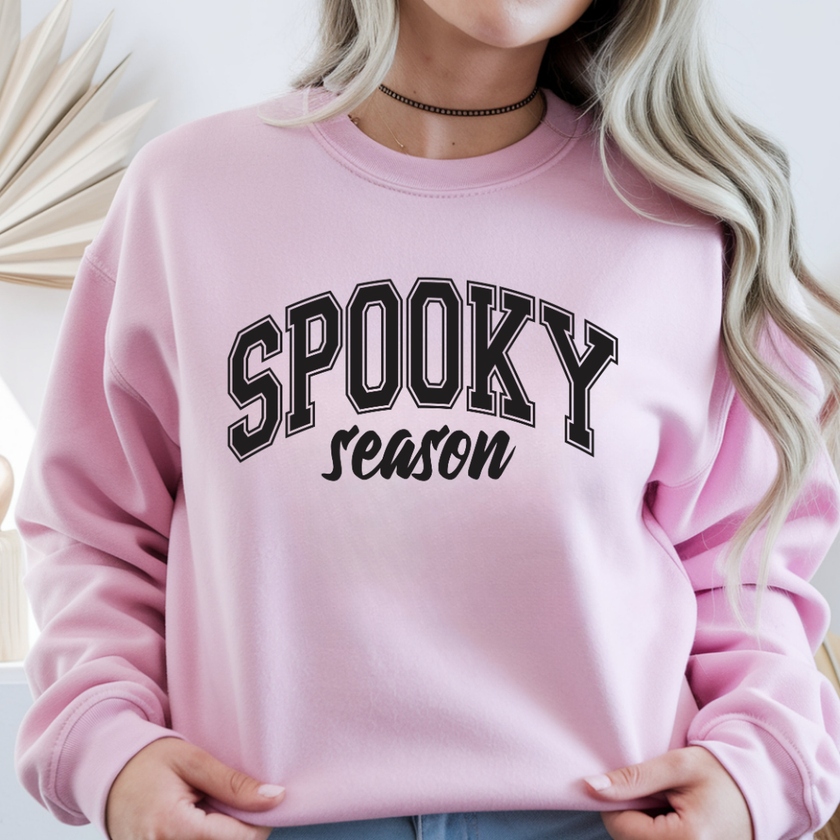 Woman wearing a light pink Spooky Season crewneck sweatshirt with black varsity Halloween lettering