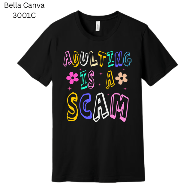 Black graphic T-shirt with bright rainbow text that says ‘Adulting Is a Scam.’ A humorous and relatable gift idea