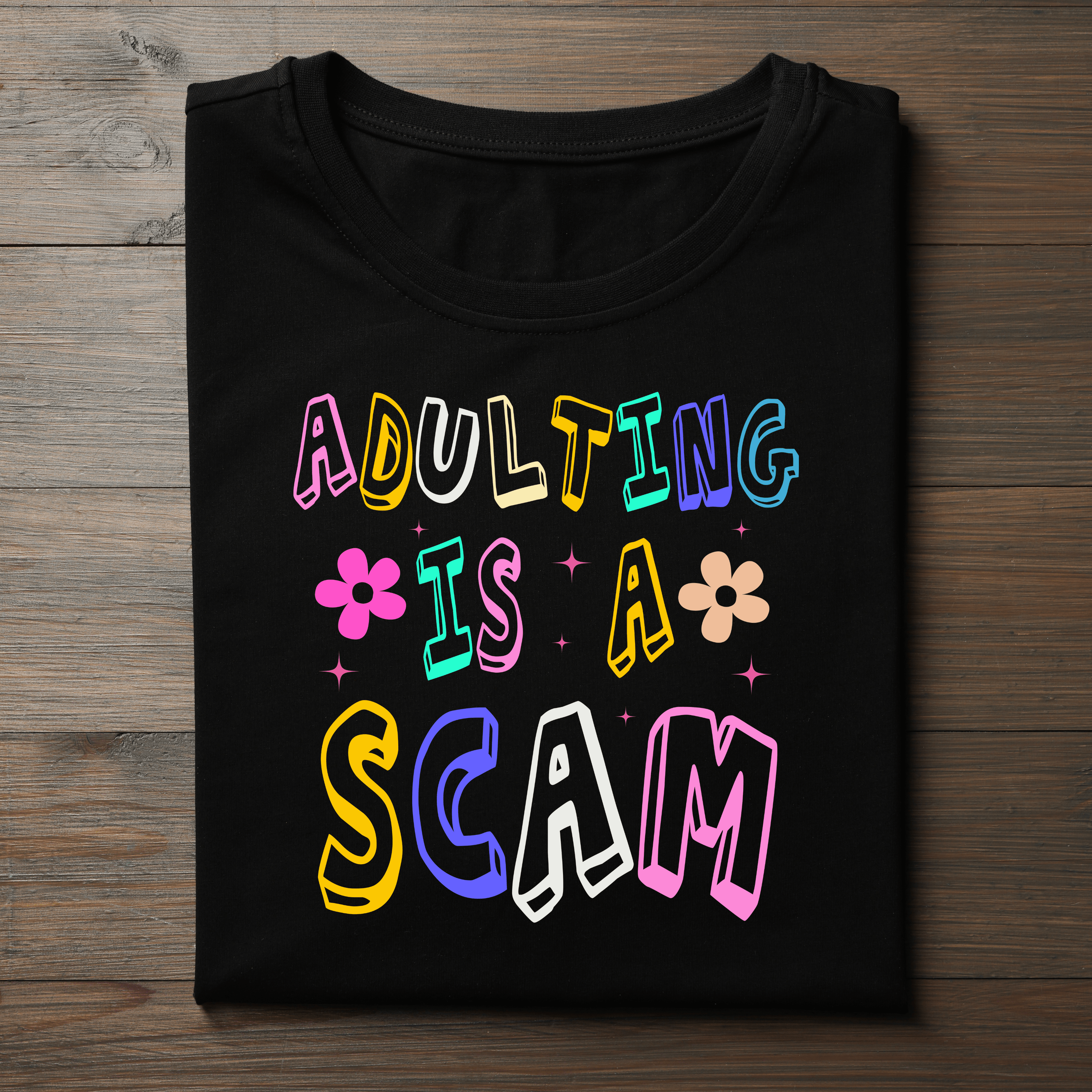 ‘Adulting Is a Scam’ in colorful retro-style font. Ideal for casual wear, birthday gifts, or anyone who loves a good laugh.
