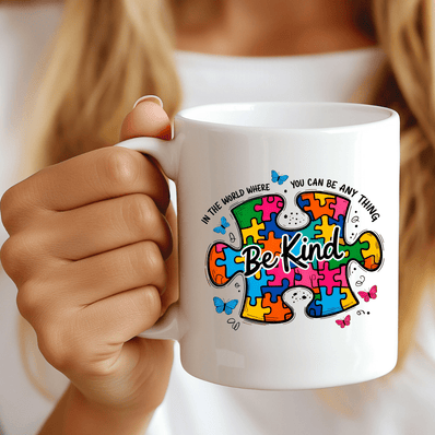 hand holding autism awareness be kind puzzle mug with colorful puzzle design