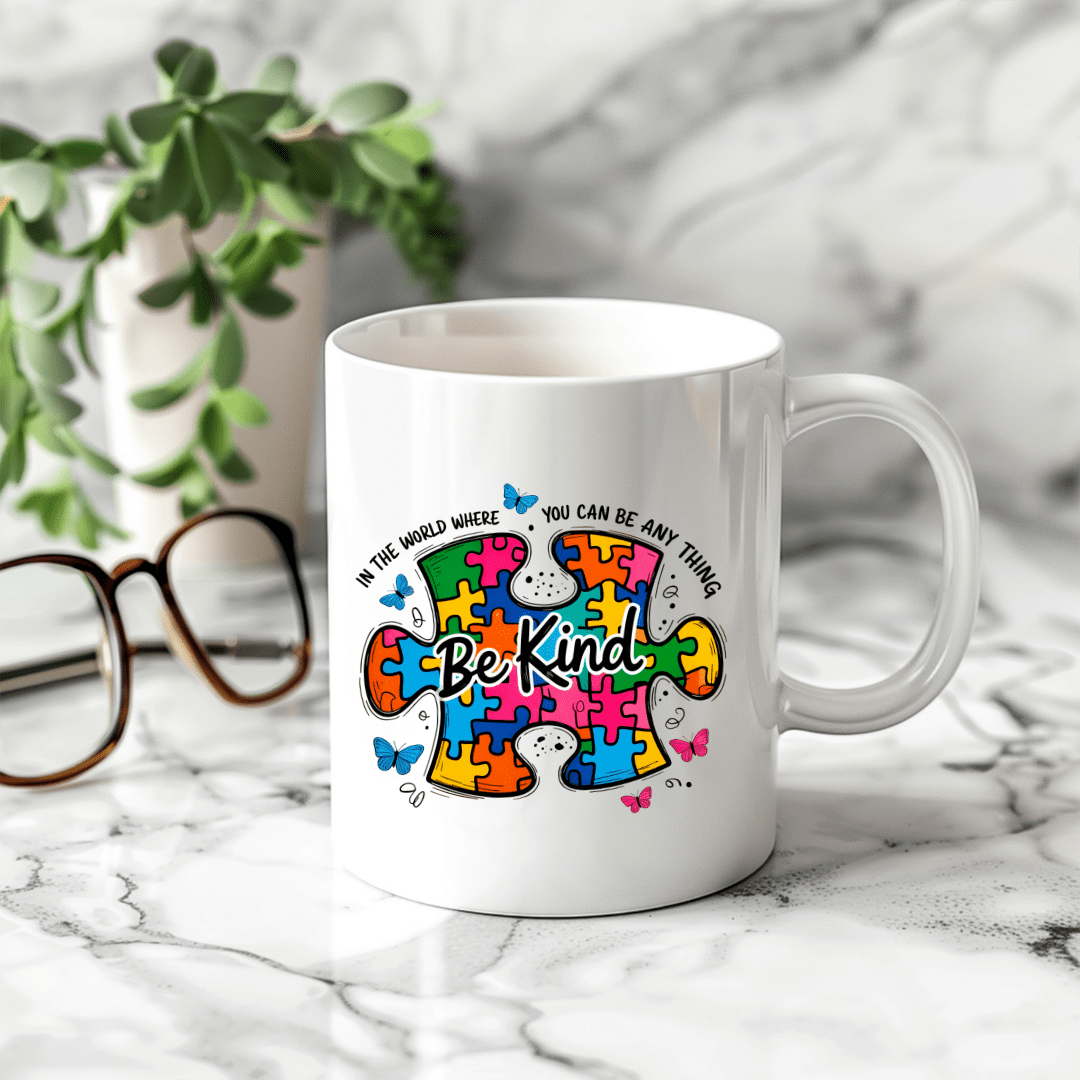 white ceramic mug with colorful autism awareness puzzle design and be kind message