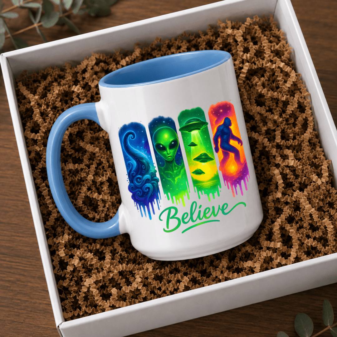 Blue accent Believe UFO Bigfoot mug displayed in a gift box with vibrant alien and cryptid artwork on the front.