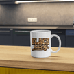 White Black History mug with bold lettering sitting on wood kitchen counter with blurred background.