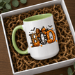 Green accent Halloween mug with BOO lettering, pumpkin details and ghost artwork styled in a gift box setting