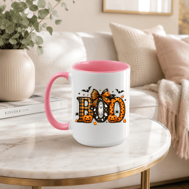 Pink accent ceramic mug with BOO design, pumpkins and bats shown as a cute Halloween gift idea for women