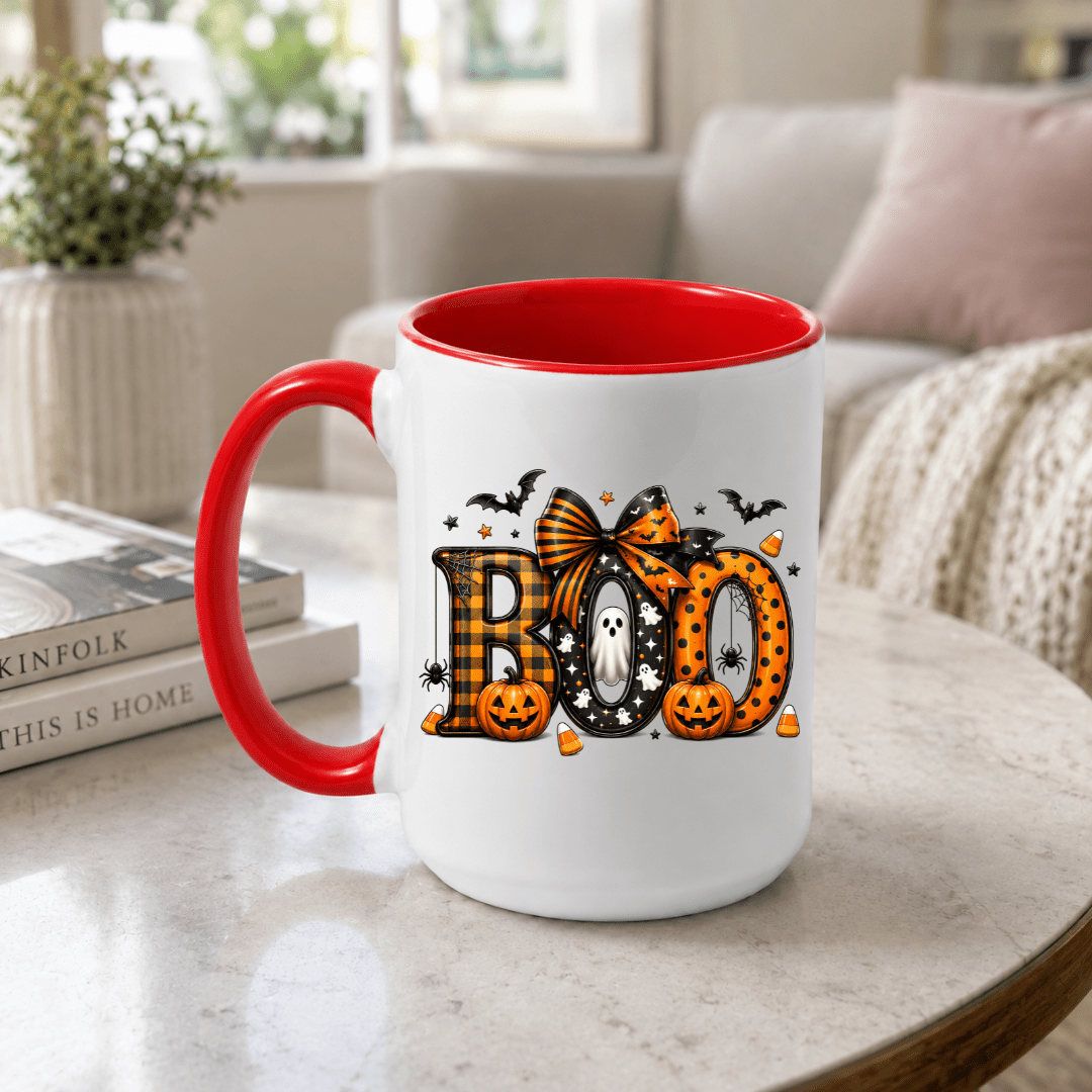 Red accent BOO coffee mug with cute Halloween graphics displayed on a living room table for festive fall styling