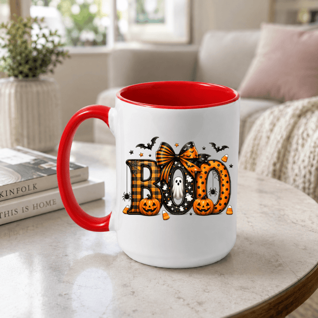 Red accent BOO coffee mug with cute Halloween graphics displayed on a living room table for festive fall styling
