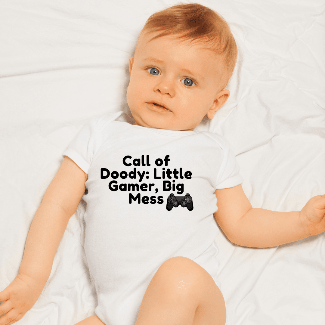 Cute infant in Call of Doody Little Gamer Big Mess bodysuit lying on bed