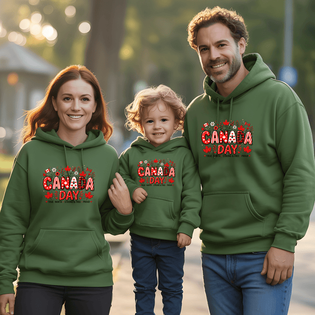 Parents and child in forest green Canada Day hoodies celebrating Canadian pride together