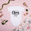 Baby onesie Chaos Creator design styled on pink background with baby toys