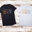 Black and white t-shirts with colorful text design on a wooden surface