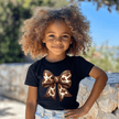 Stylish girls boutique graphic shirt with detailed cow print bow design paired with casual youth fashion apparel.