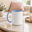 A white ceramic mug with a blue interior and blue handle sits on a marble table in a softly lit living room setting.