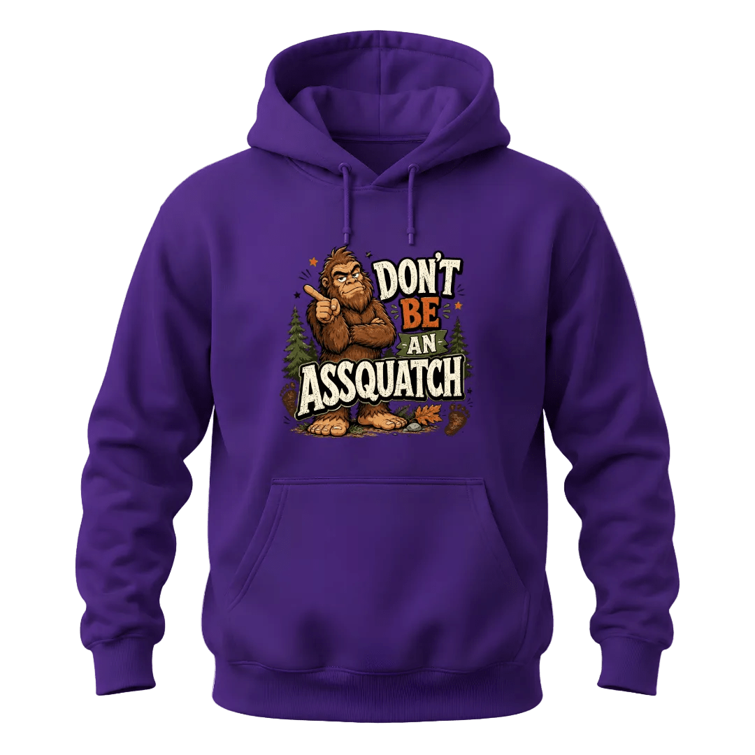 Purple graphic hoodie featuring a humorous Sasquatch design with pine trees, footprints, and Don’t Be An Assquatch lettering.