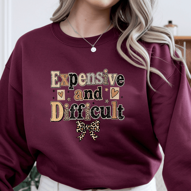 Maroon crewneck sweatshirt for women featuring Expensive and Difficult vintage typography graphic with leopard print bow design.