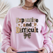 Pink women's sweatshirt featuring a stylish Expensive and Difficult graphic design with leopard bow detail and feminine fashion aesthetic.