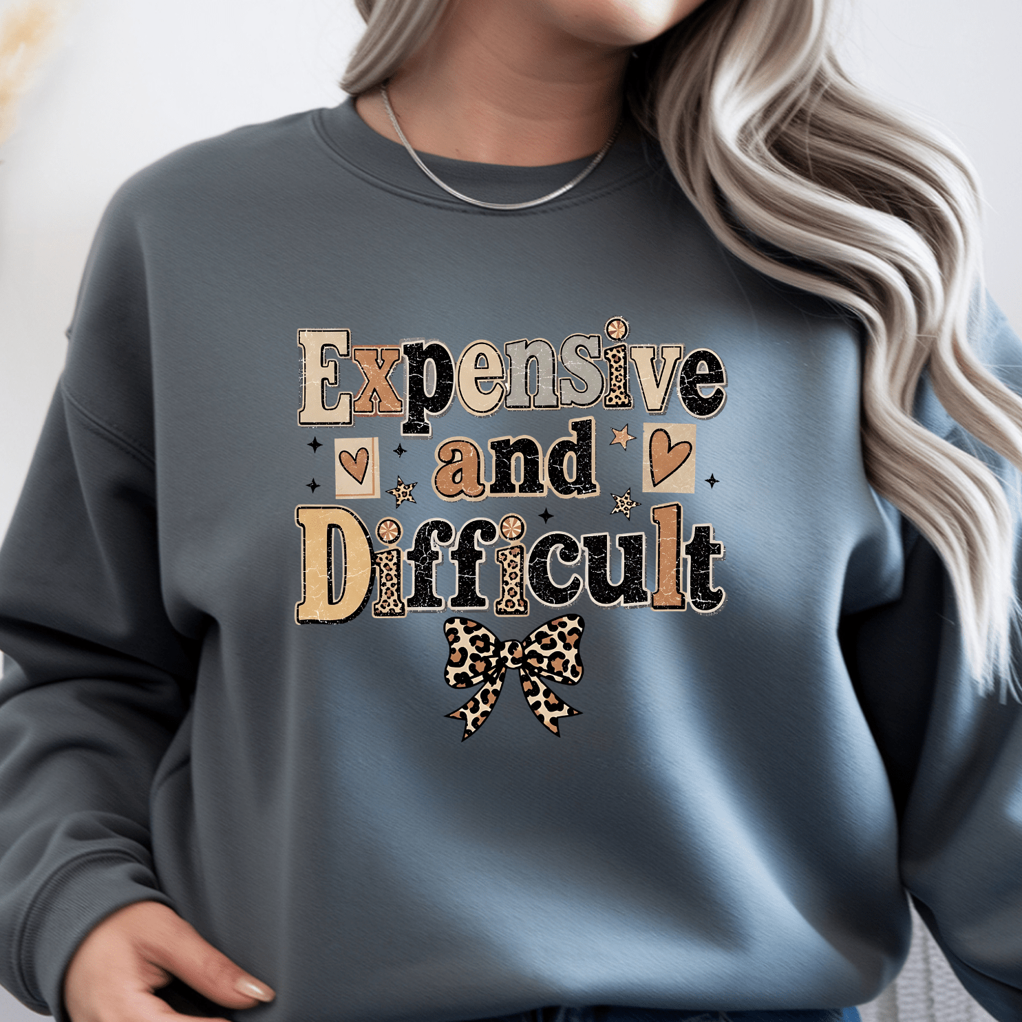 Charcoal gray women's crewneck sweatshirt featuring Expensive and Difficult graphic print with leopard bow accent and trendy boutique style.