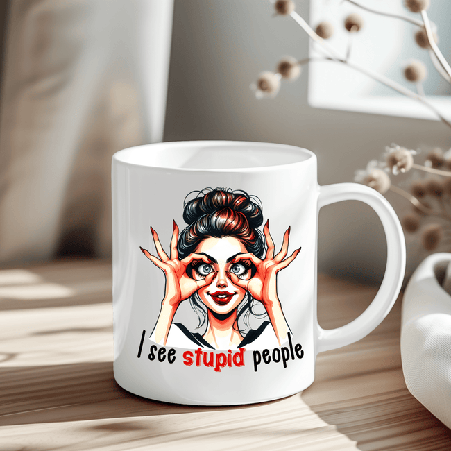 White ceramic mug featuring a cartoon woman with wide eyes and the phrase “I See Stupid People.”