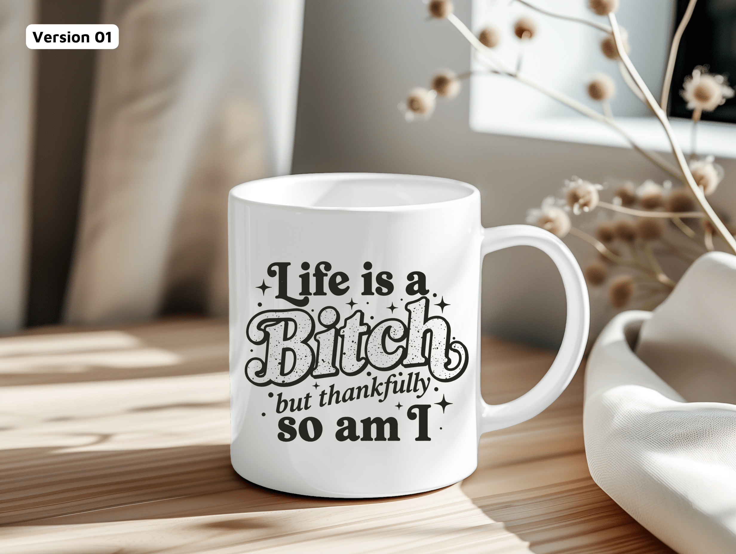 Funny mug displayed in a cozy home setting, neutral decor, featuring the phrase “Life Is a Bitch but Thankfully So Am I.”