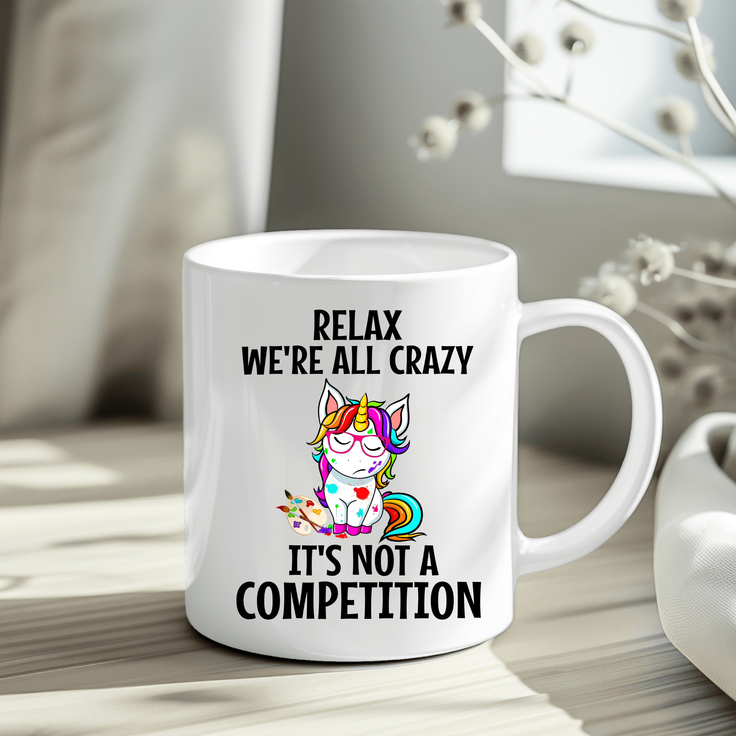 Funny unicorn mug with rainbow unicorn and “Relax We’re All Crazy” quote on white ceramic cup.