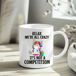 Funny unicorn mug with rainbow unicorn and “Relax We’re All Crazy” quote on white ceramic cup.