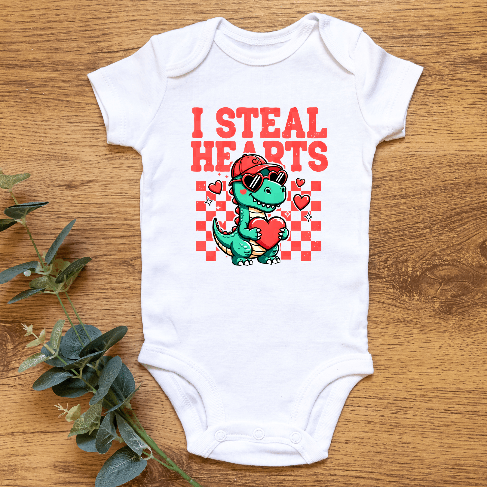 Baby outfit flat lay featuring I Steal Hearts graphic onesie