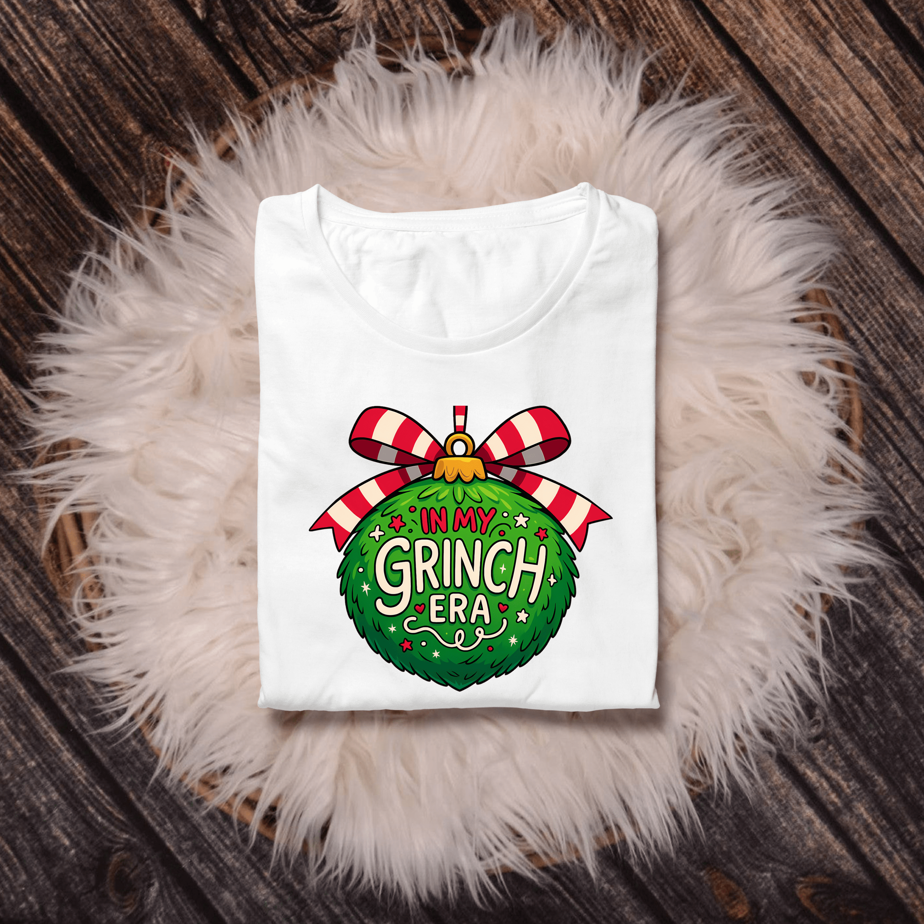 Festive In My Grinch Era graphic T-shirt featuring green ornament and red bow. Funny Christmas shirt for the holiday season.