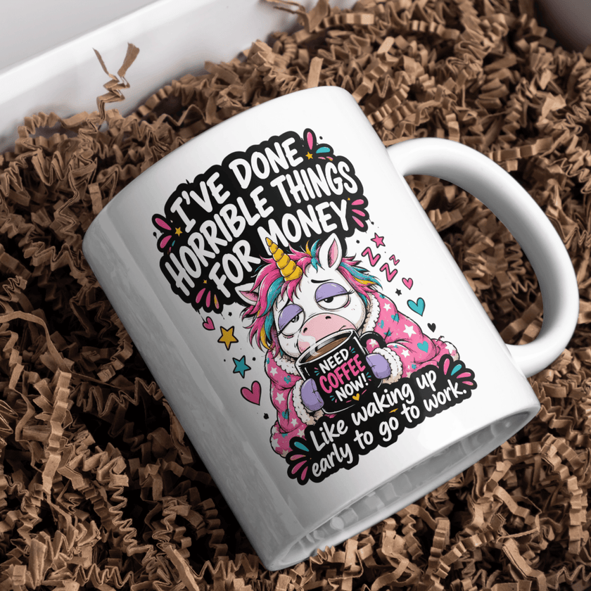 White ceramic funny unicorn coffee mug featuring the quote I've Done Horrible Things for Money Like Waking Up Early to Go to Work on a marble kitchen countertop.