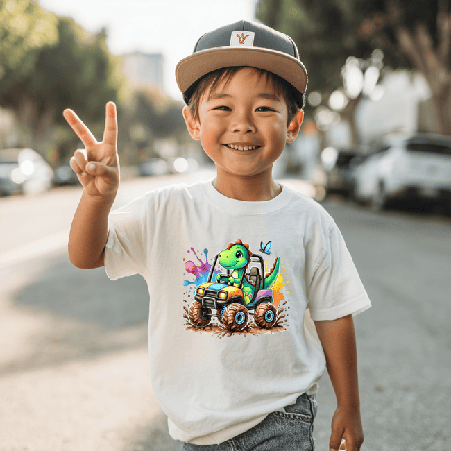 White t-shirt  kids graphic T shirt with a cheerful green dinosaur driving a colorful monster truck design.
