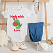 Baby onesie with 'Happy Valentine's Day' text, blue pants, and shoes on a wooden rack.