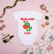 Cute dinosaur baby bodysuit laying on pink background