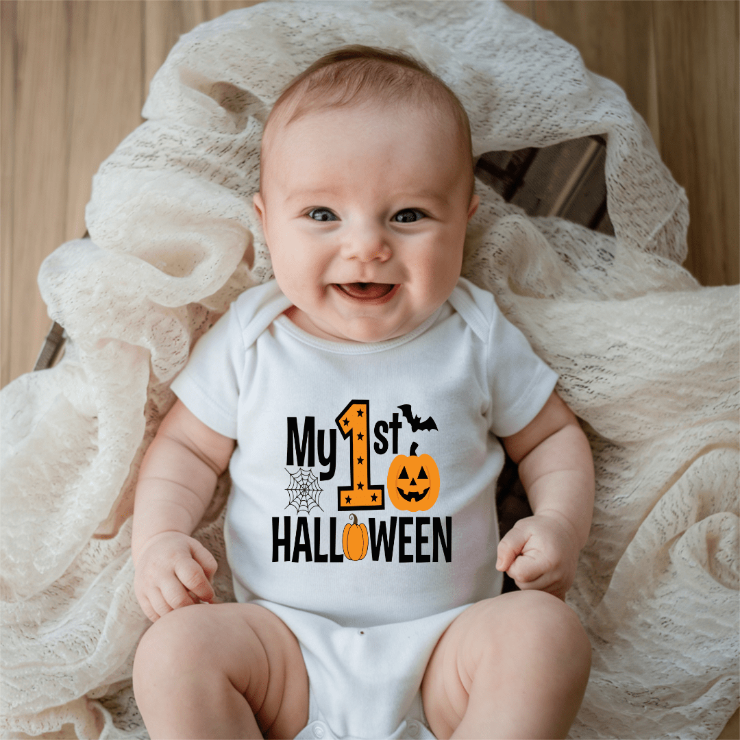 Smiling baby wearing a white My First Halloween baby onesie with orange pumpkin, bat and spiderweb graphic.