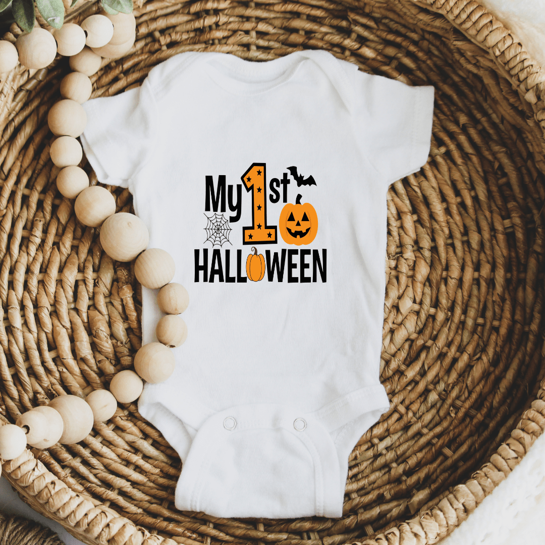 White baby Halloween bodysuit displayed in a woven basket with My First Halloween pumpkin graphic.