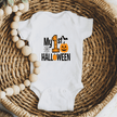White baby Halloween bodysuit displayed in a woven basket with My First Halloween pumpkin graphic.