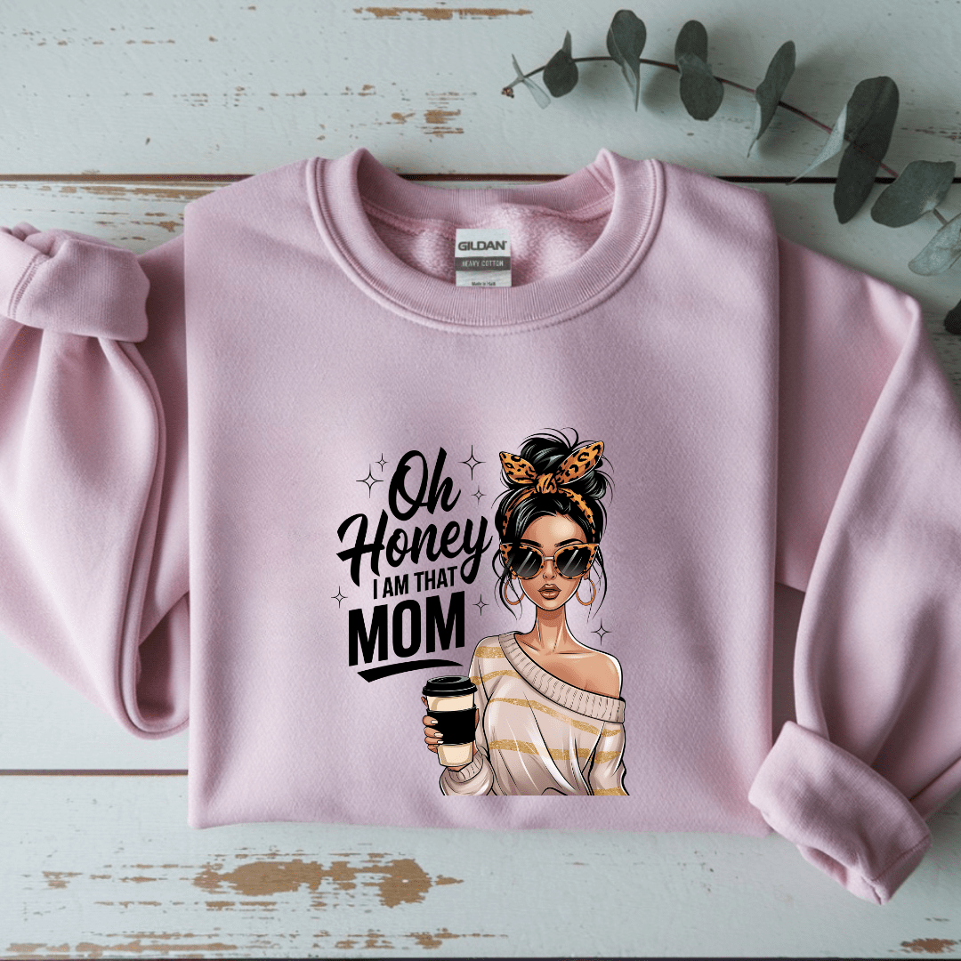 Pink sweatshirt with a graphic of a woman holding a coffee cup and text 'Oh Honey I am that Mom' on a light blue background.