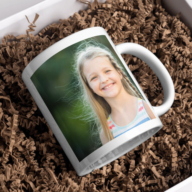 White mug with a photo of a young girl on a bed of brown paper shreds