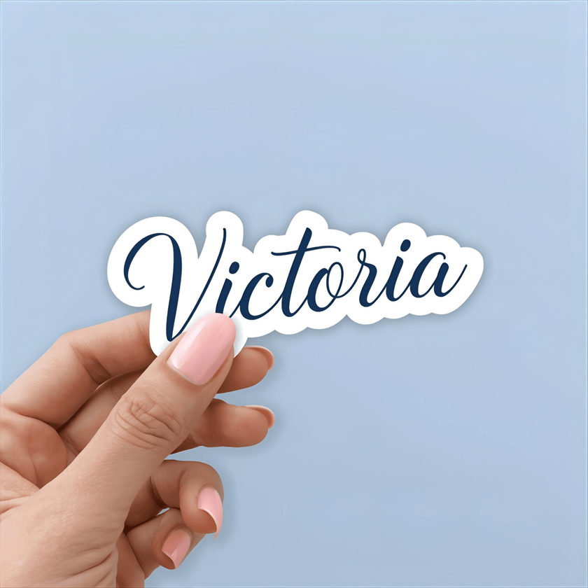 Hand holding a sticker with 'Victoria' text against a light blue background
