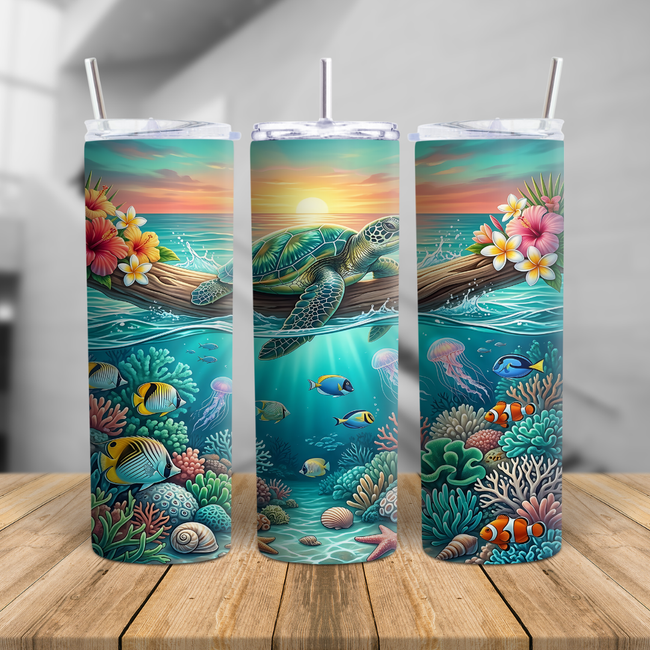 Sea turtle skinny tumbler cup featuring a tropical sunset, coral reef, fish, shells, and ocean artwork, shown on a beach with a clear lid and metal straw.