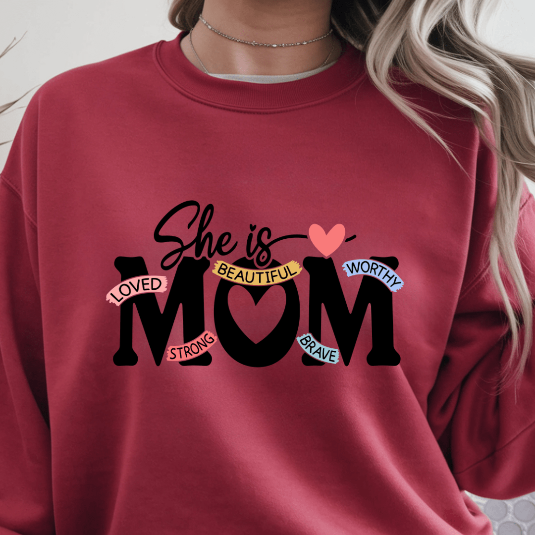Red crewneck sweater with inspirational She Is Mom text graphic centered on front