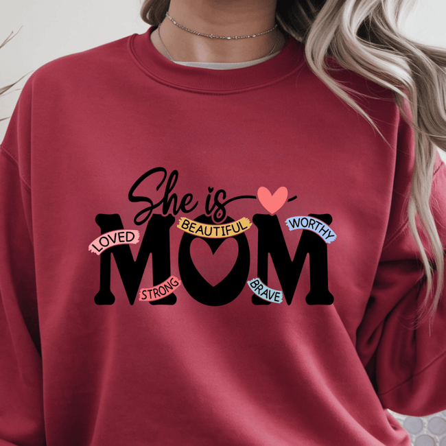 Red crewneck sweater with inspirational She Is Mom text graphic centered on front