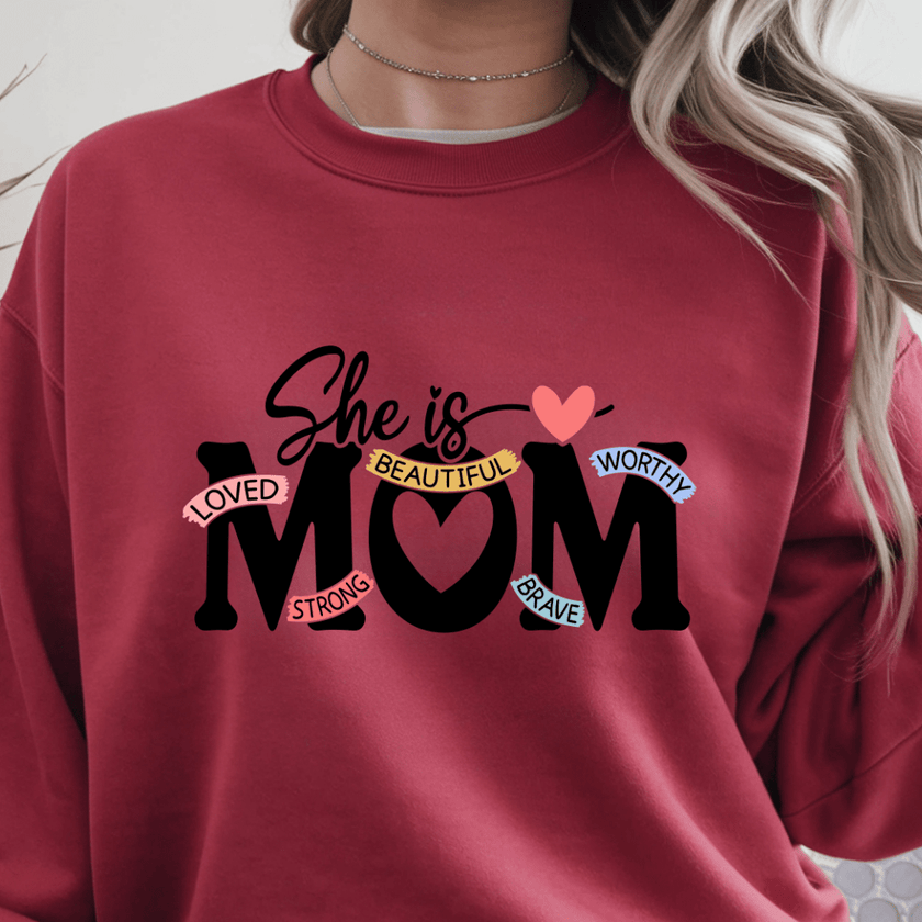 Red crewneck sweater with inspirational She Is Mom text graphic centered on front