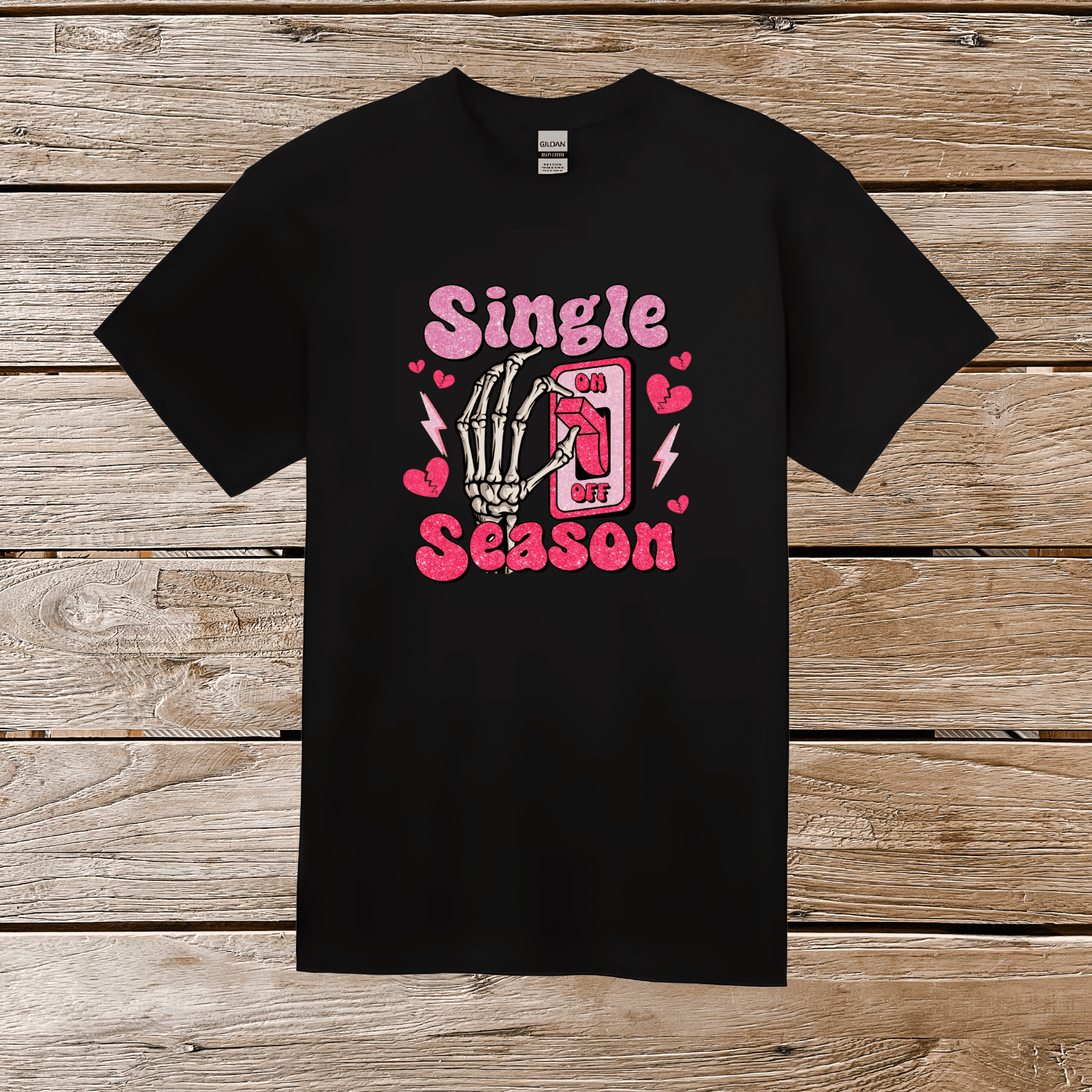 Close-up of black graphic tee with vibrant pink glittery skeleton hand OFF switch and playful hearts