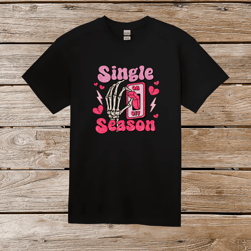 Close-up of black graphic tee with vibrant pink glittery skeleton hand OFF switch and playful hearts