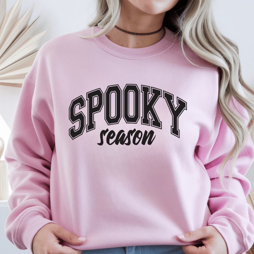 Woman wearing a light pink Spooky Season crewneck sweatshirt with black varsity Halloween lettering
