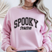 Woman wearing a light pink Spooky Season crewneck sweatshirt with black varsity Halloween lettering