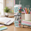 Thoughtful teacher gift tumbler with school themed artwork, inspirational quotes, colorful classroom details, lid, and straw.